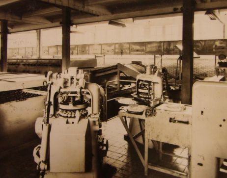 Het uitrolapparaat, de verdeelbolmachine en het begin van de doppenbaan bollenbakovens in de moderne fabriek van Hooimeijer.